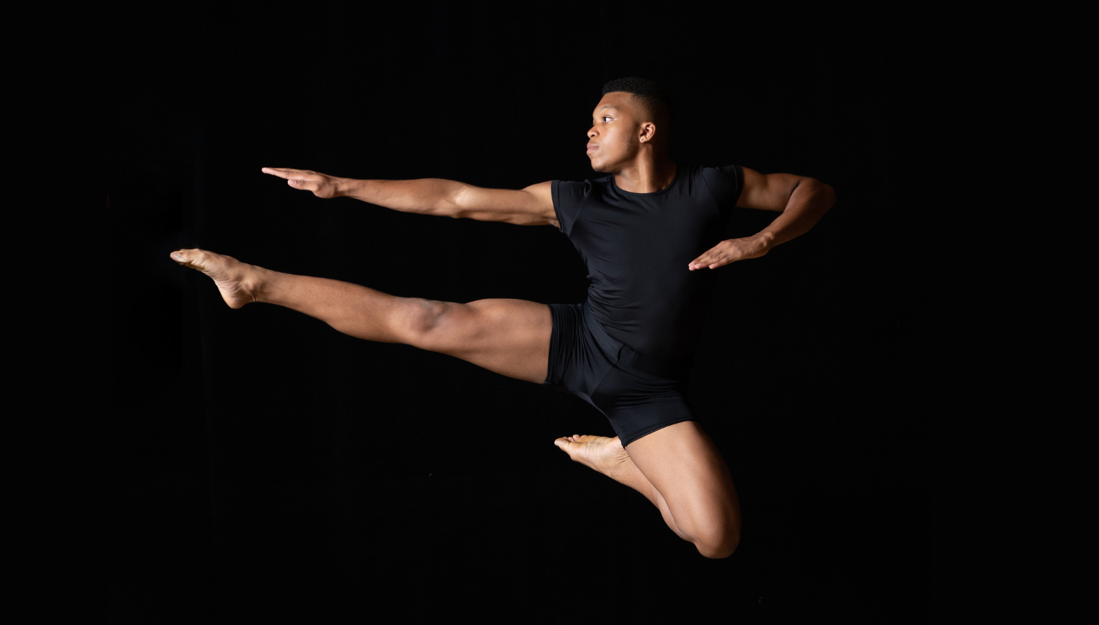 Dancer jumps in the air with right leg and arm extended