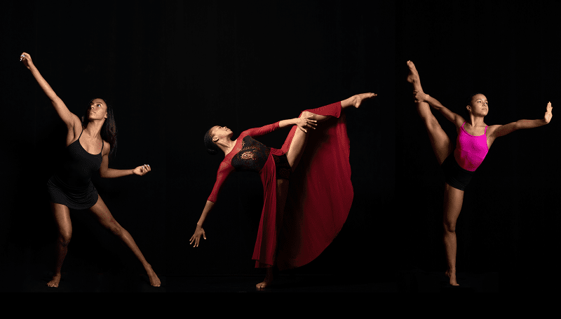 Three dancers posing against a black background