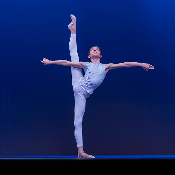 Male dancer with right leg extended in air