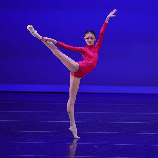 Dancer in red leotard dances onstage