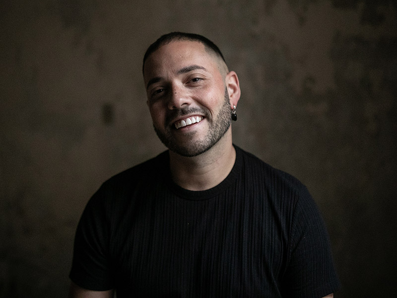 White man smiling poses in front of a green background