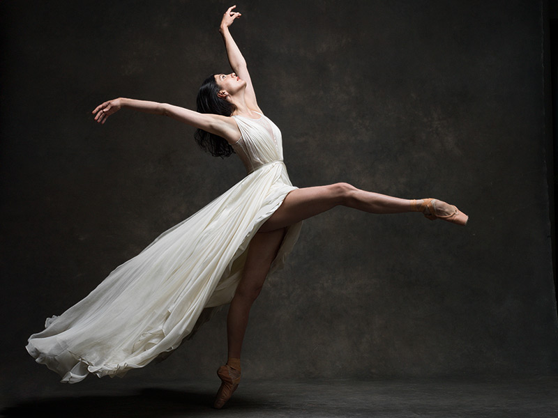 Ballet dancer in flowy white dress dancing on pointe